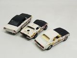 three toy cars are lined up in a row on a white surface
