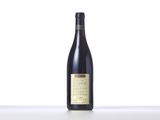 a bottle of wine sitting on top of a table next to a white wall