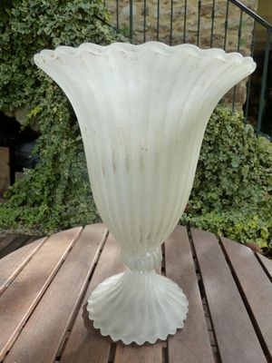 a glass vase sitting on a wooden table on a patio