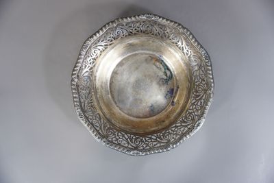 une assiette en argent posée sur une table blanche, sur fond noir