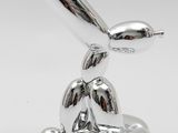 an image of a silver sculpture of a dog with a baseball bat in its mouth
