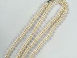 a close up of a white pearl necklace on a white surface