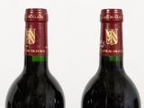 two bottles of red wine sitting next to each other on top of a table