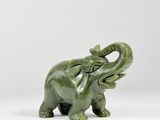 une statue d'éléphant verte posée sur une surface blanche