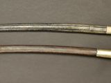 pair of antique swords on a table with a black background