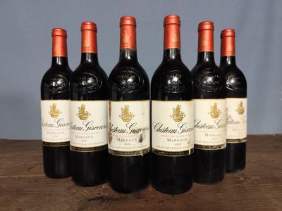 six bottles of red wine are lined up on a wooden table