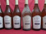 six bottles of wine are lined up in a row on a pink background