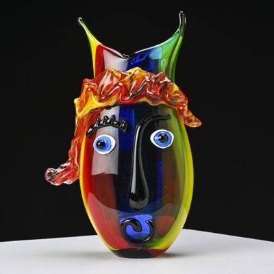 un vase coloré orné d'un visage, posé sur une table