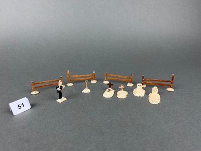 a small group of miniature figurines of people in a fenced in area