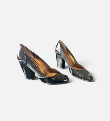 une paire d'escarpins noirs et argentés posés sur une surface blanche