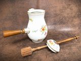 a white vase with a wooden handle next to a brush