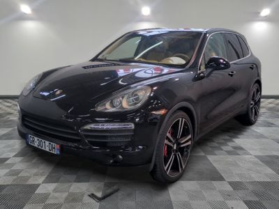 La Porsche Cayenne noire est garée sur un sol en carrelage à damier.