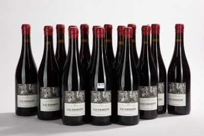 six bottles of red wine lined up on a white surface
