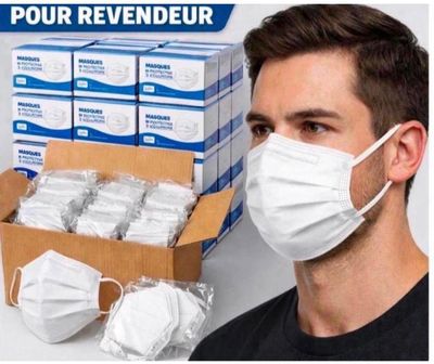 un homme portant un masque, à côté d'une boîte de masques jetables