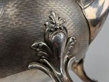 a silver tea pot on a stand on a table