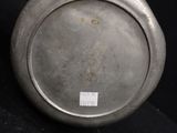 a silver plate on a black surface with a sticker on it