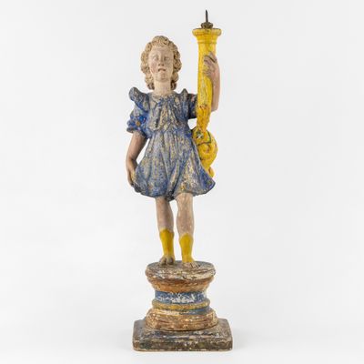 une vieille statue en bois représentant une jeune fille tenant une bougie, posée sur un socle