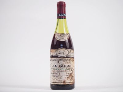 une vieille bouteille de vin posée sur une table blanche