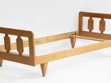 un petit lit avec un cadre en bois sur fond blanc