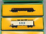 trois trains miniatures dans leurs boîtes, posés sur une table