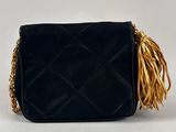 a black quilted purse with gold fringes on a white background