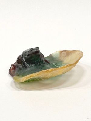 a figurine of a frog in a shell on a white surface