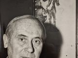 photographie en noir et blanc d'un homme en costume-cravate assis devant un tableau