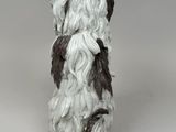 statue of a dog with long hair sitting on top of a white surface
