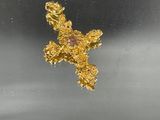 a gold cross with a pink stone in it