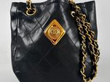 a close up of a black purse with a gold chain