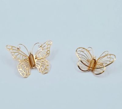une paire de boucles d'oreilles papillon en or sur fond blanc