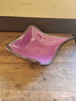 purple glass bowl sitting on top of a wooden table next to a wall