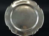 une assiette en argent posée sur un socle, sur un fond noir