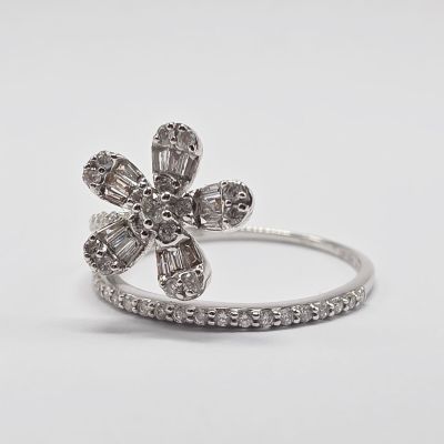 un gros plan d'une bague en forme de fleur sertie d'un diamant, sur fond blanc