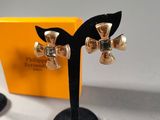 pair of silver and black flower earrings on black stand next to a yellow box