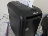 une déchiqueteuse noire posée sur un bureau, à côté d'une bouteille d'eau