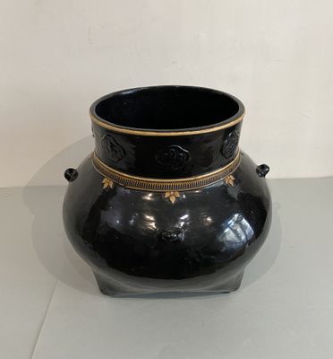 a black vase with gold decoration on it on a table