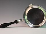a silver pan with a black handle sitting on a table