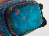 someone is holding a ring with a blue stone inside of it