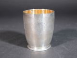 an old silver cup sitting on top of a table next to a black background