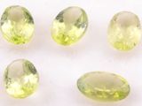 four oval cut green peridotites on a white surface