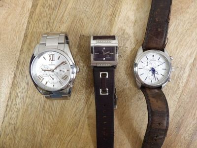 two watches are sitting next to each other on a wooden table