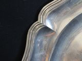 three silver plates on a black table with a black background