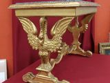 une table dorée sur laquelle se trouve un oiseau, posée sur une table rouge