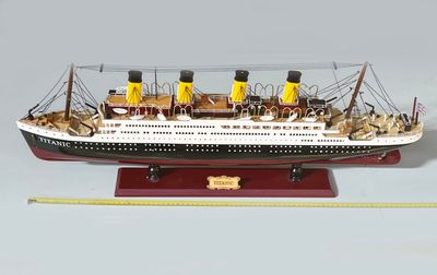une maquette de bateau posée sur un socle à côté d'une règle
