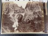 an old photo of a bridge in the middle of a mountain
