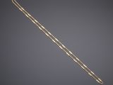a gold necklace with a long chain on a gray background