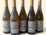 six bouteilles de vin sont alignées sur une surface blanche