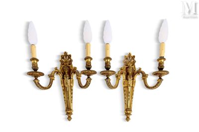 three brass wall sconces with candles on each of them