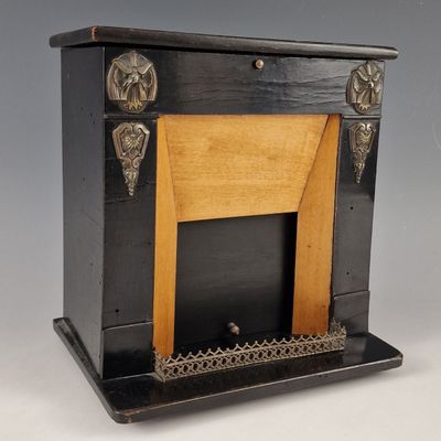 une cheminée ancienne noire et dorée, avec un manteau en bois